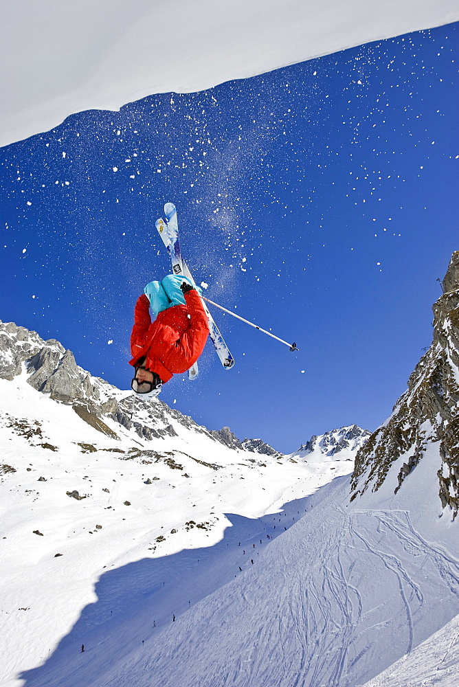 A man performs a back flip off a cornice while skiing off-piste near St. Anton am Arleberg, Austria.