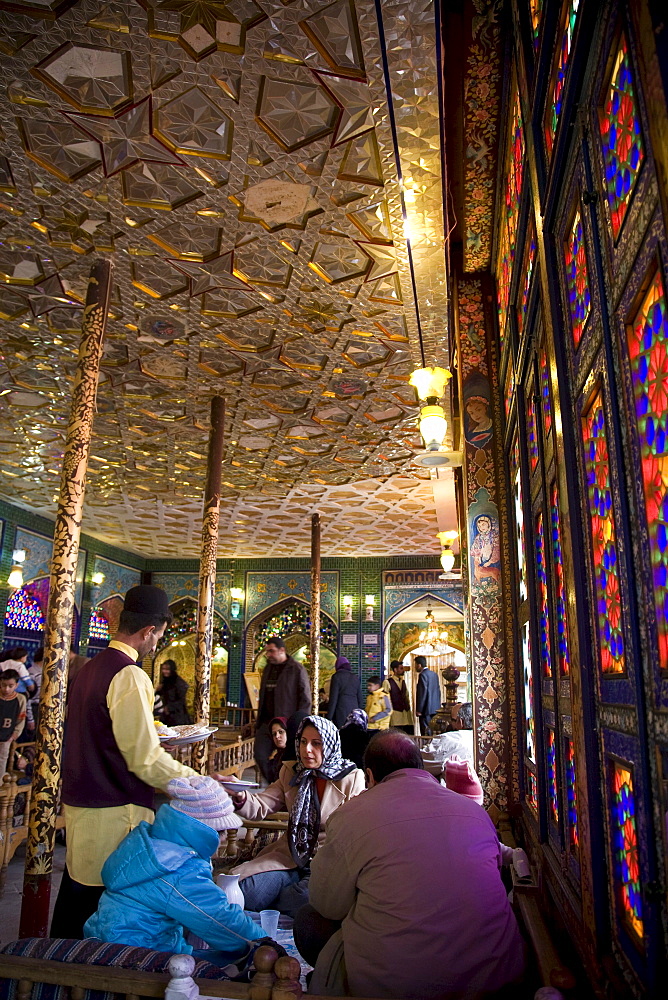 Esfahan, Iran - February, 2008: Iranian family having lunch in a colorful traditional looking restaurant on Imam Square in Esfahan, Iran.