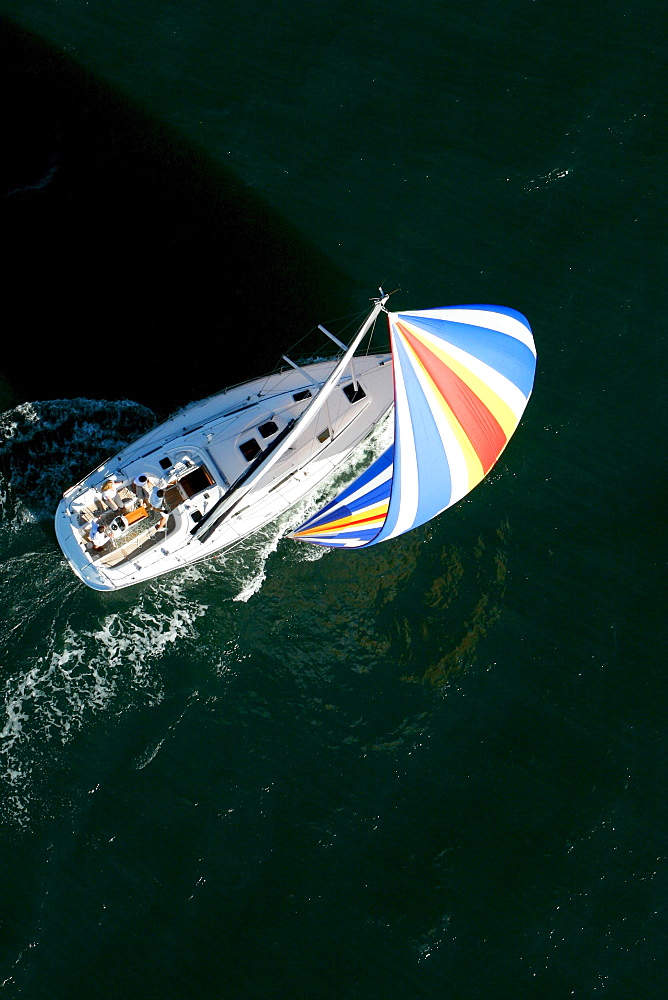 Aerial view of a sailing yacht with a colorful spinnaker cruising in Pittwater on the North Shore from Sydney, Australia.