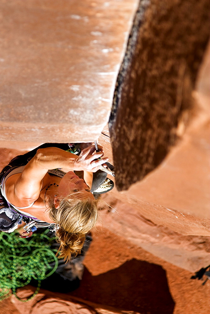 A female rock climber climbs Ruby's Cafe, a classic 5.13 rated climb in Indian Creek, Utah.