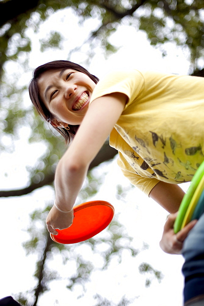 A young Asian-American woman plays flying disk golf in Baltimore, Maryland.