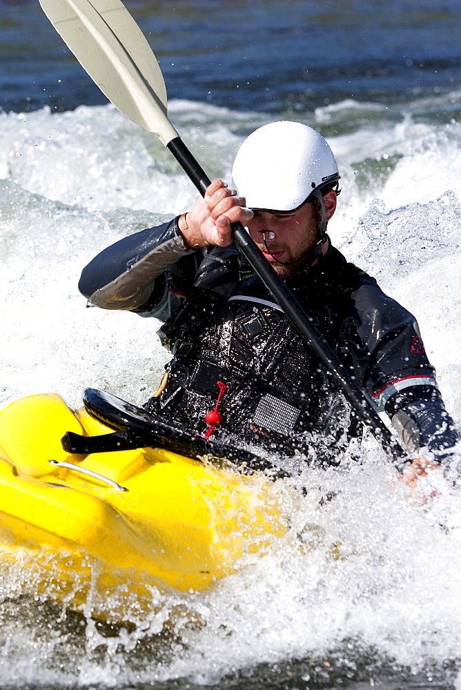 A male kayaker in a playboat paddles on the Clark Fork River, Missoula, Montana.