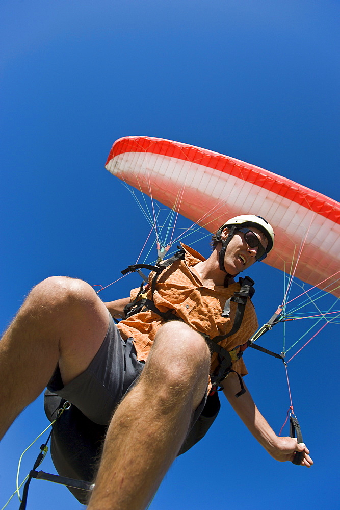 A man paraglides on a beautiful summer day.