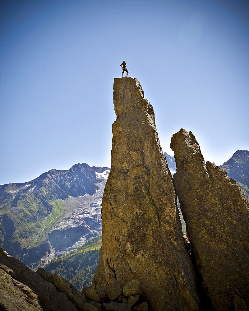 A rock climber stands on top of a pinnacle that he just completed in  the French Alps.