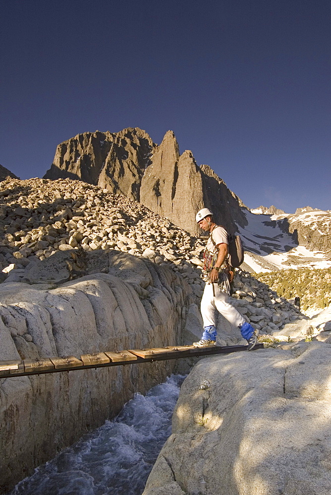 Rock climber walks across bridge.