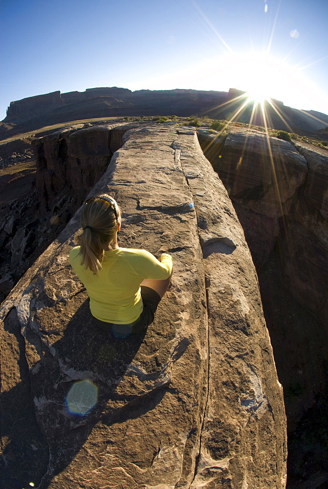 Woman in yoga pose on sandstone arch, Canyonlands National Park, Utah.