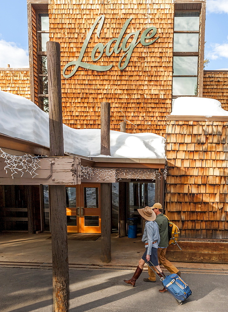 Couple with luggage walking in to the lodge