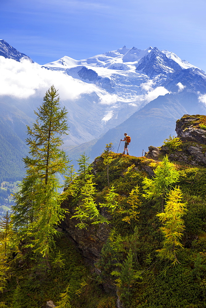 A female hiker is enjoying the view near Embd, in the Swiss Alps. This region of Wallis, close to Zermatt, is famous for the outdoor activities one can do. It is a paradise for hikers, climbers, mountainbikers and nature lovers. In the background the Nadelgrat range, with the Ried glacer coming down the hill.