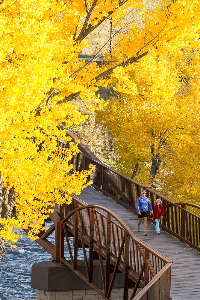 A mother and daughter walking over the Animas River on a bridge on the Animas River Trail in Durango, Colorado.