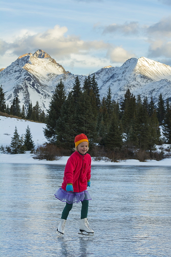 A girl ice skating on early season ice, Molas Lake, San Juan National Forest, Silverton, Colorado.