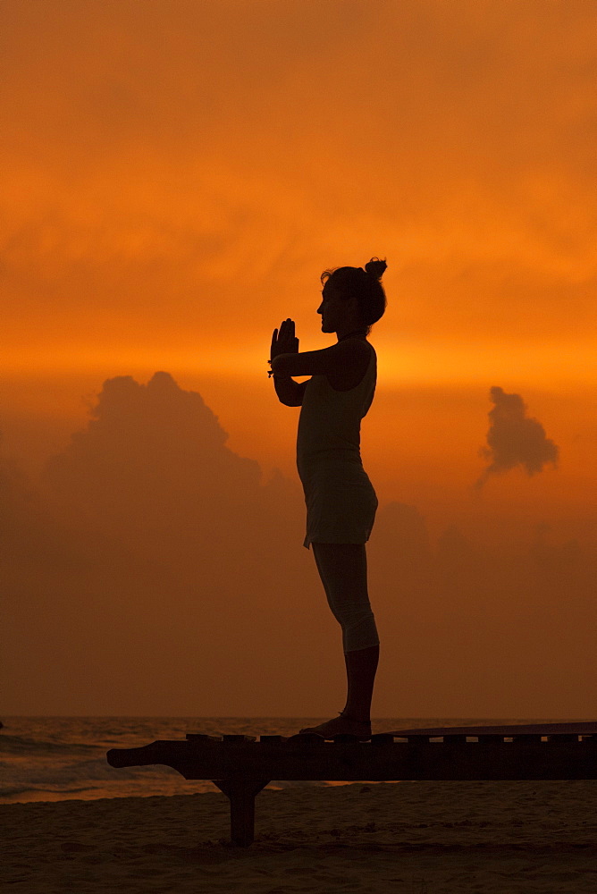 Girl doing yoga at sunset on the beach in Sri Lanka