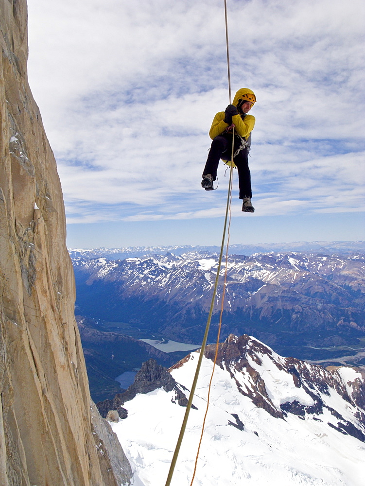 A climber rappels down Cerro Fitz Roy's south face, with distant peaks and lakes of Argentine Patagonia in the distance. Cerro Fitz Roy is one of the most massive peaks in the Southern Andes, and is a sought after summit by the world's top alpinists. It was named in honor of the captain of Darwin's ship, the Beagle, Captain Robert FitzRoy, who explored the region. The indigenous name for the peak is Chalten, which means "smoking mountain". , Argentina