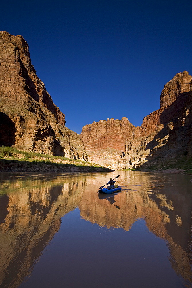 A person paddling an inflatable kayak duckie down the Colorado river, Utah.