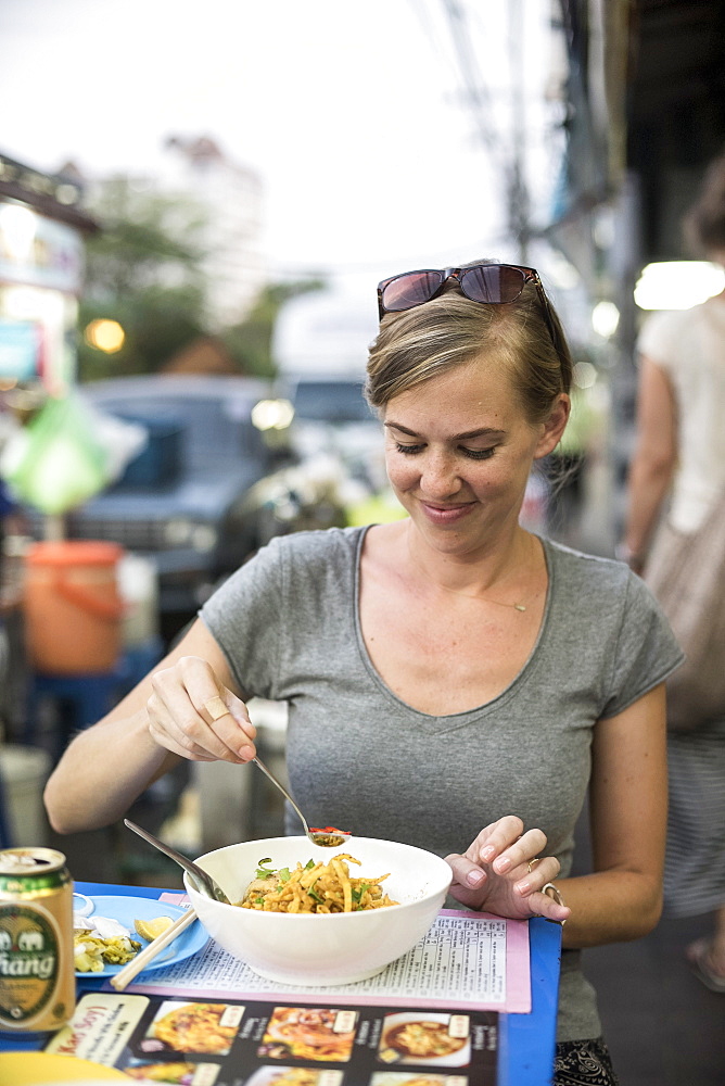 A woman eats a noodle bowl called kao soi at an outdoor food stand in Chiang Mai, Thailand, on April 30, 2015.