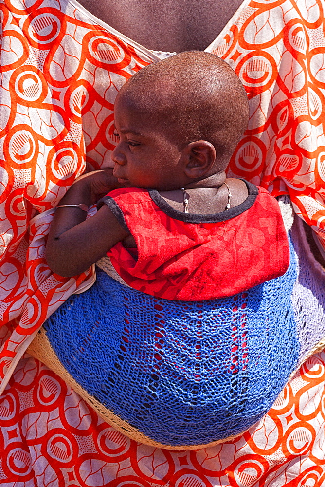 African bedik woman carrying a child while doing housework,  ziguinchor, casamance, Senegal, Africa