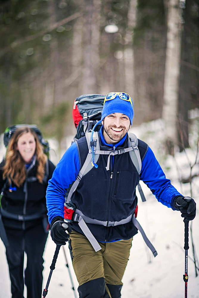 Two Hikers Trekking Through A Forest In Maine