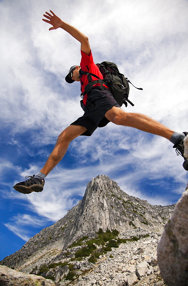 Low Angle View Of Male Backpacker Jumping In British Columbia