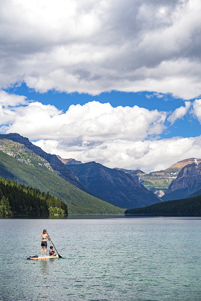 Woman Paddleboarding With Child In Bowman Lake At Glacier National Park