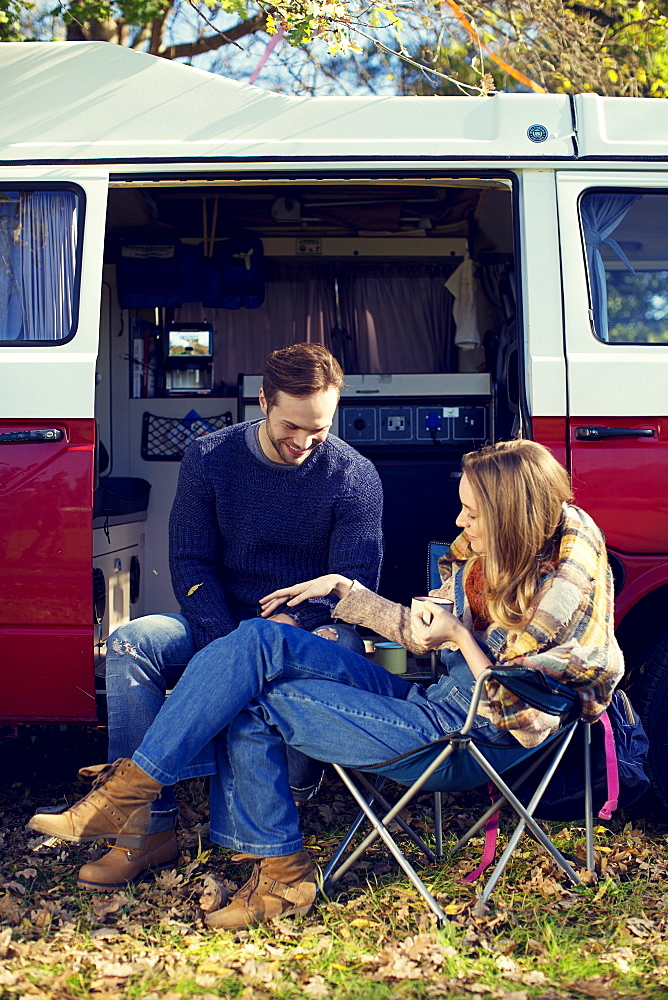 Young couple having coffee in front of caravan