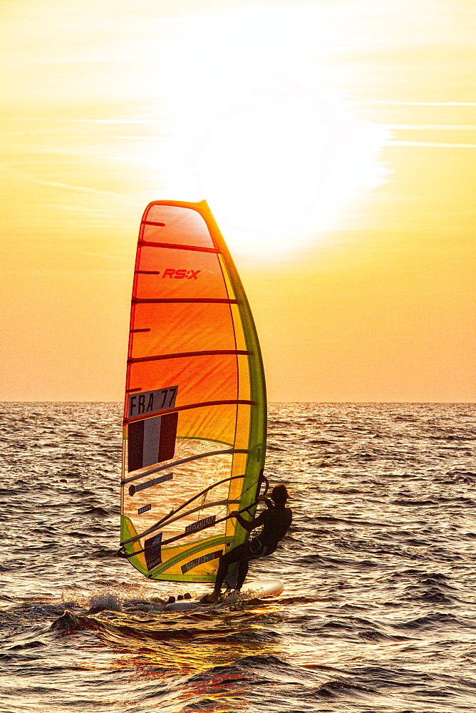 Pink Granite CoastPierre Le Coq riding his windsurf board during a sunset session on the "Cote de Granit Rose" ( Pink Granite Coast ), Trégastel, Brittany, France.