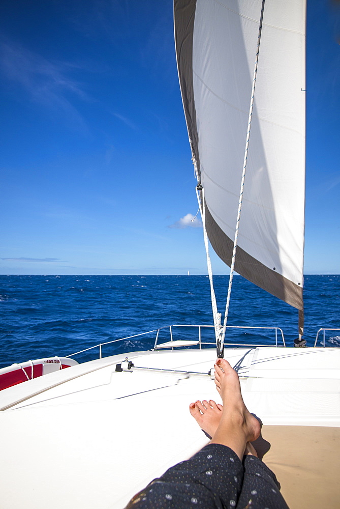 Low section view with feet of woman sunbathing on sailboat sailing in sea