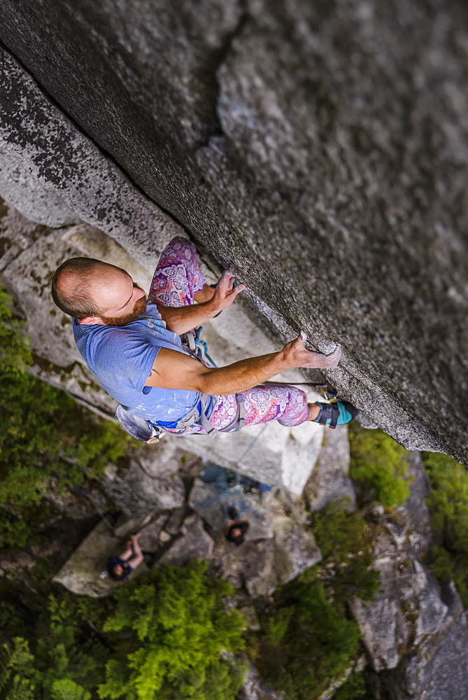 View from above of young man rock climbing, Squamish, British Columbia, Canada