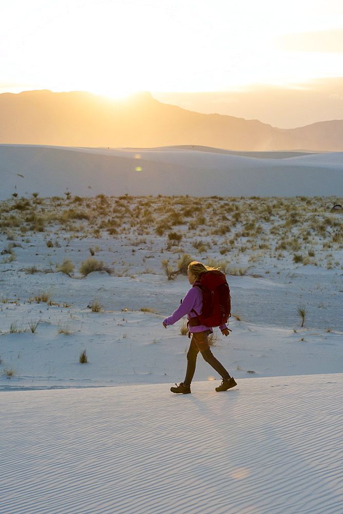 Side view of girl hiking at sunset in White Sands National Monument, Alamogordo, New Mexico, USA