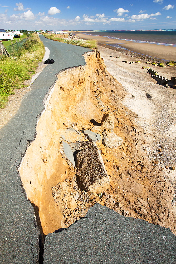 A collapsed coastal road at between Skipsea and Ulrome on Yorkshires East Coast, near Skipsea, UK. The coast is composed of soft boulder clays, very vulnerable to coastal erosion. This section of coast has been eroding since Roman times, with many villages having disappeared into the sea, and is the fastest eroding coast in Europe. Climate change is speeding up the erosion, with sea level rise, increased stormy weather and increased heavy rainfall events, all playing their part.