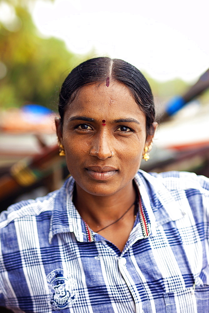 Head and shoulders portrait of mature woman with black hair looking at camera, Kerala, India