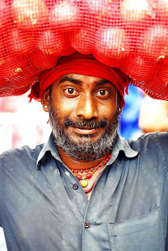 Head ands shoulders portrait of mid adult man with beard and mustache carrying sack on head, Kerala, India