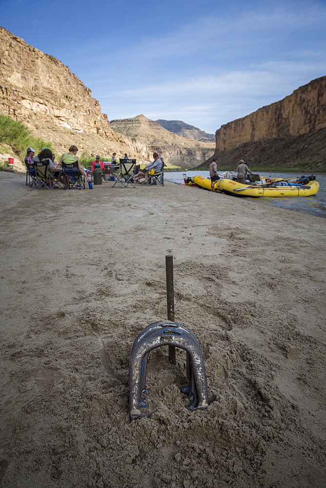 Horseshoes lying on sand with people camping on riverbank of Green River in background, Utah, USA