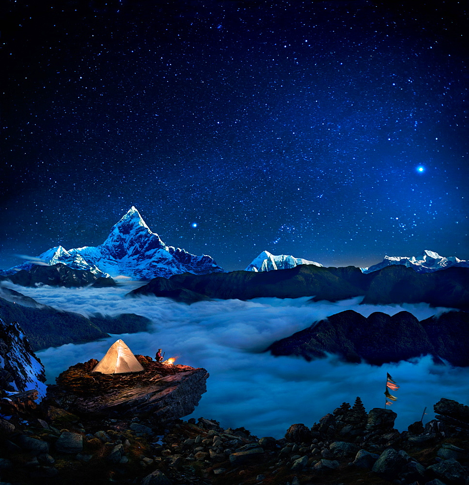 Starry sky over camper at bonfire on rock formation overlooking sea of clouds and mountains, Pokhara, Kaski, Nepal