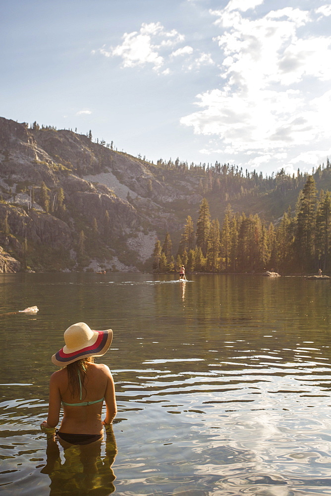 Rear view of woman in bikini and with sun hat standing in lake, Shasta, California, USA