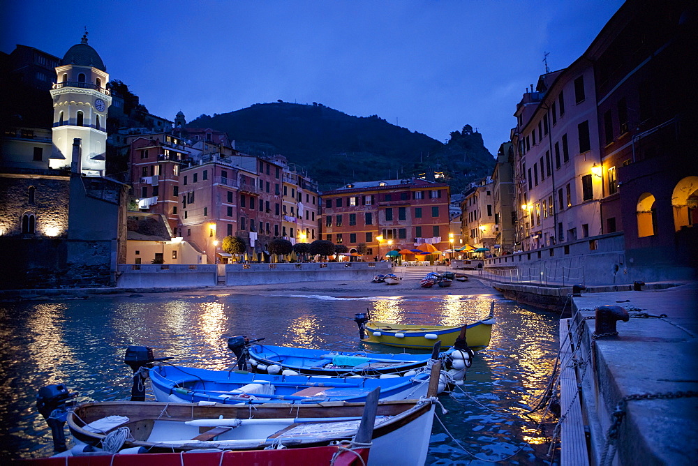 Boats Moored By Buildings Along The Waterfront At Night; Vernazza Liguria Italy