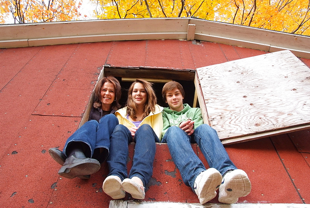 Mom with two teenagers sitting in the loft window of a barn, Simcoe, Ontario, Canada