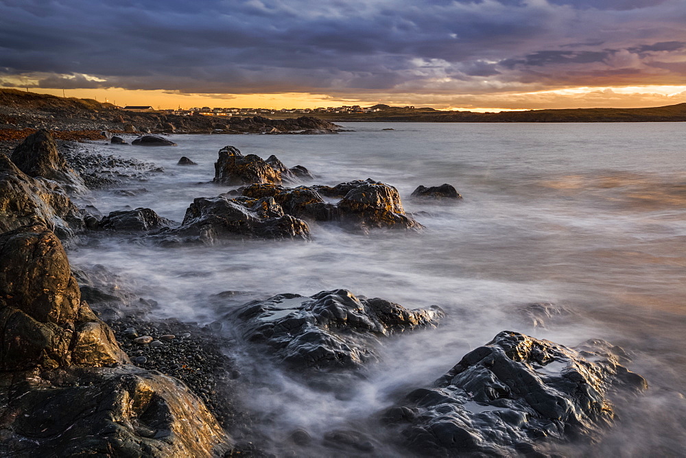 The rugged Atlantic coastline at sunrise under a cloudy sky; Bonavista, Newfoundland, Canada
