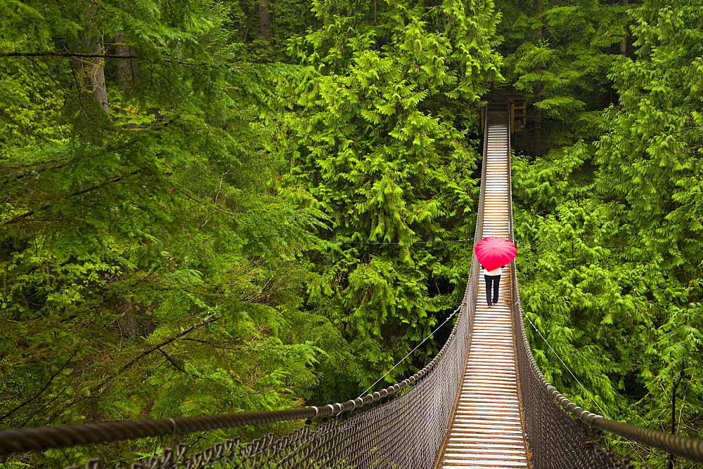 Woman With A Red Heart-Shaped Umbrella Crossing The Lynn Canyon Suspension Bridge, North Vancouver; Vancouver, British Columbia, Canada