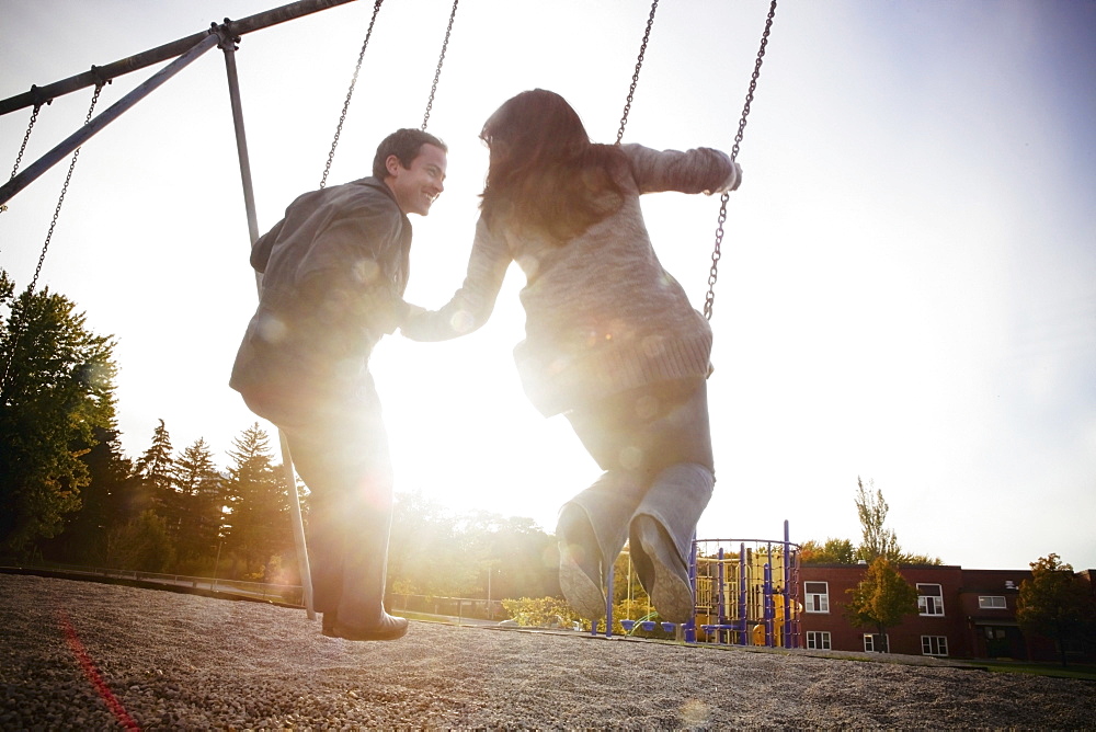 Hamilton, Ontario, Canada, A Couple On The Swings At The Playground