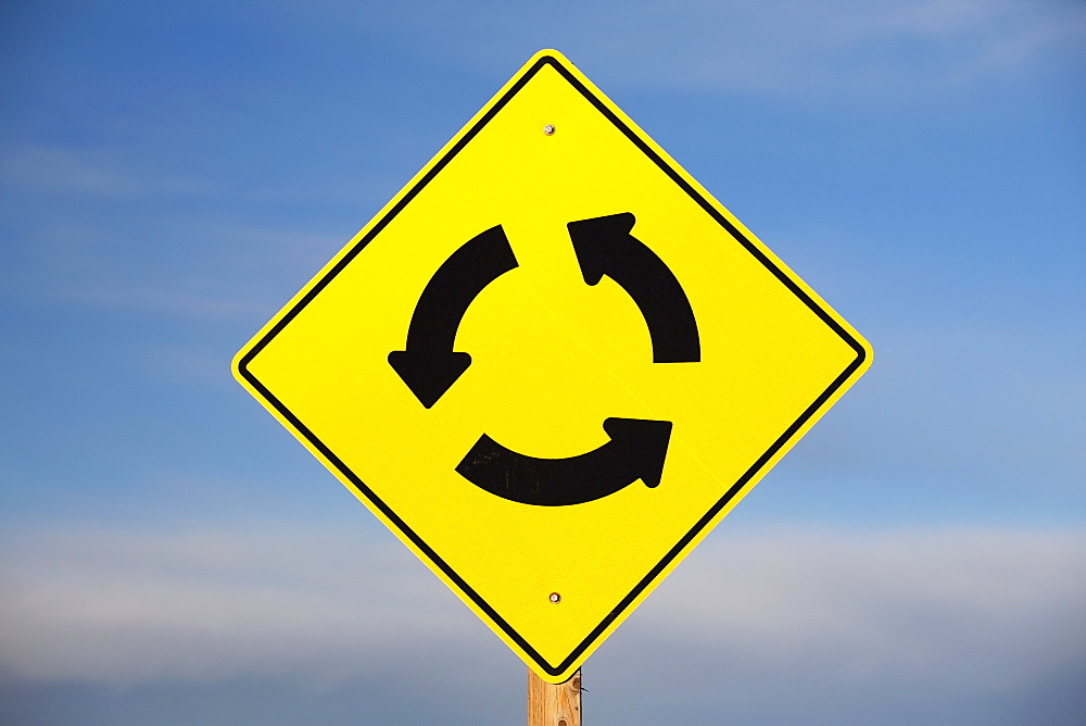 A Yellow Sign Showing Three Arrows Going In A Circle, Calgary, Alberta, Canada