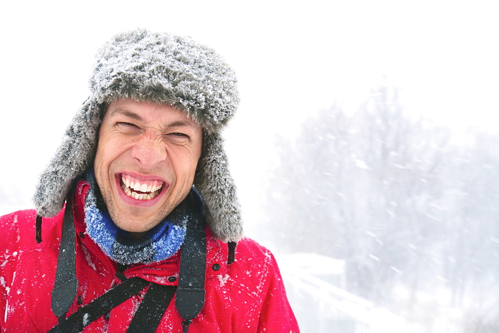 A Young Man Laughing A He Wears A Fur Hat Covered In Snow On A Snowy Day, Eagan, Minnesota, United States of America