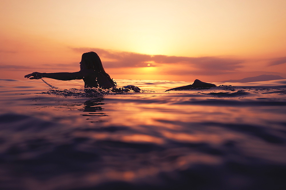 A Woman Paddling On A Surfboard At Sunset, Tarifa, Cadiz, Andalusia, Spain