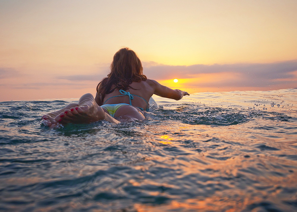 A Woman Laying On A Surfboard Watching The Sunset, Tarifa, Cadiz, Andalusia, Spain