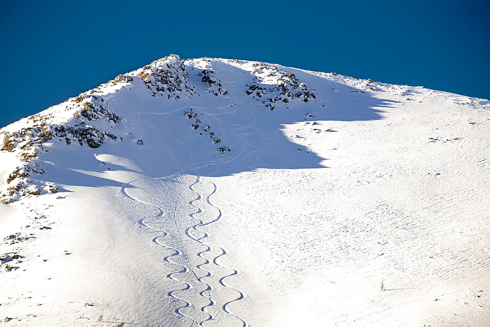 Snow covered mountain peak with skier tracks and deep blue sky, Lake louise alberta canada