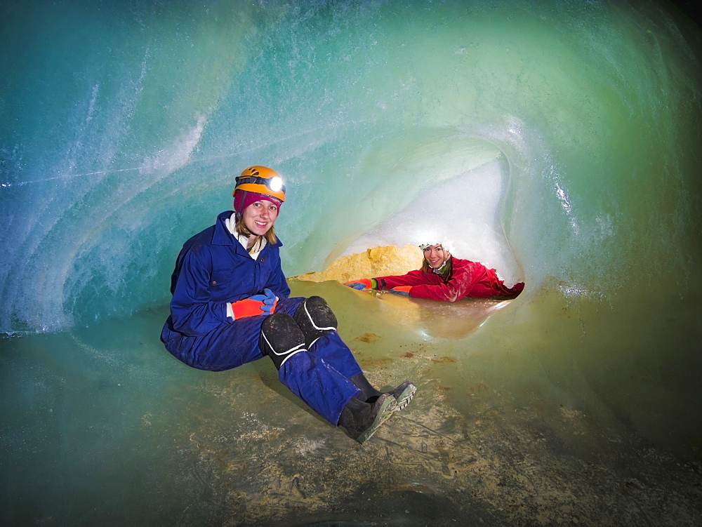 Two female cavers exploring a cave ice-plug, Crowsnest pass alberta canada