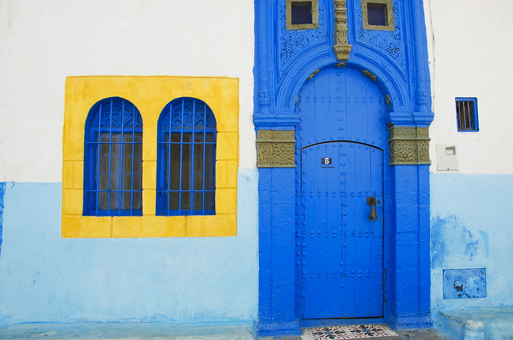 A painted blue door and bright yellow window frame on a house in old town, Rabat morocco