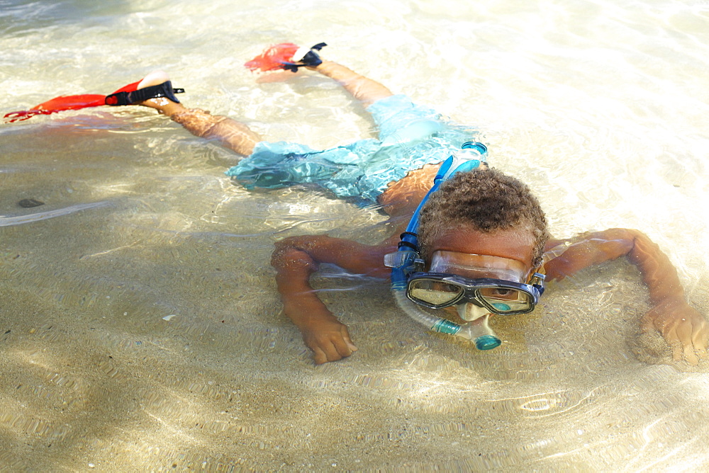 A young boy in the shallow water of the ocean with snorkelling gear, Hawaii united states of america