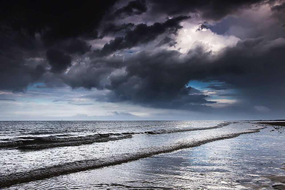 Dark storm clouds over the ocean with waves rolling into the shore, Druridge bay northumberland england