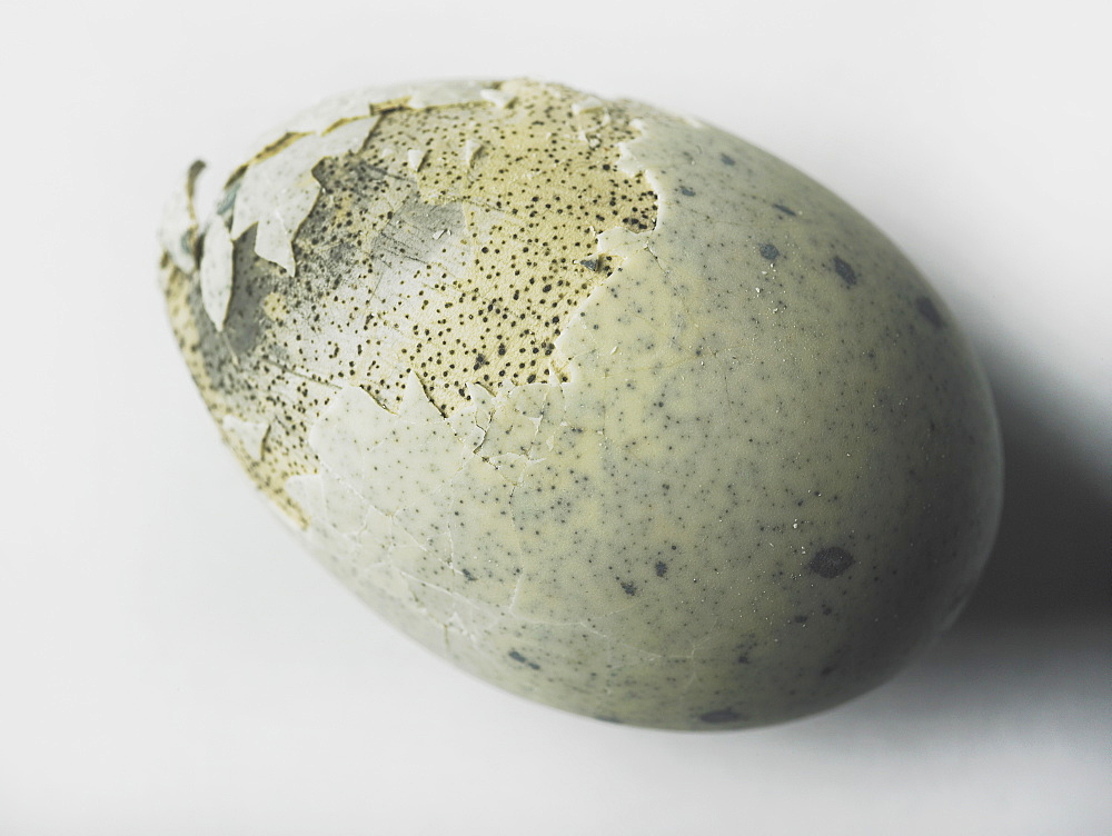 An egg with shell cracked on a white background