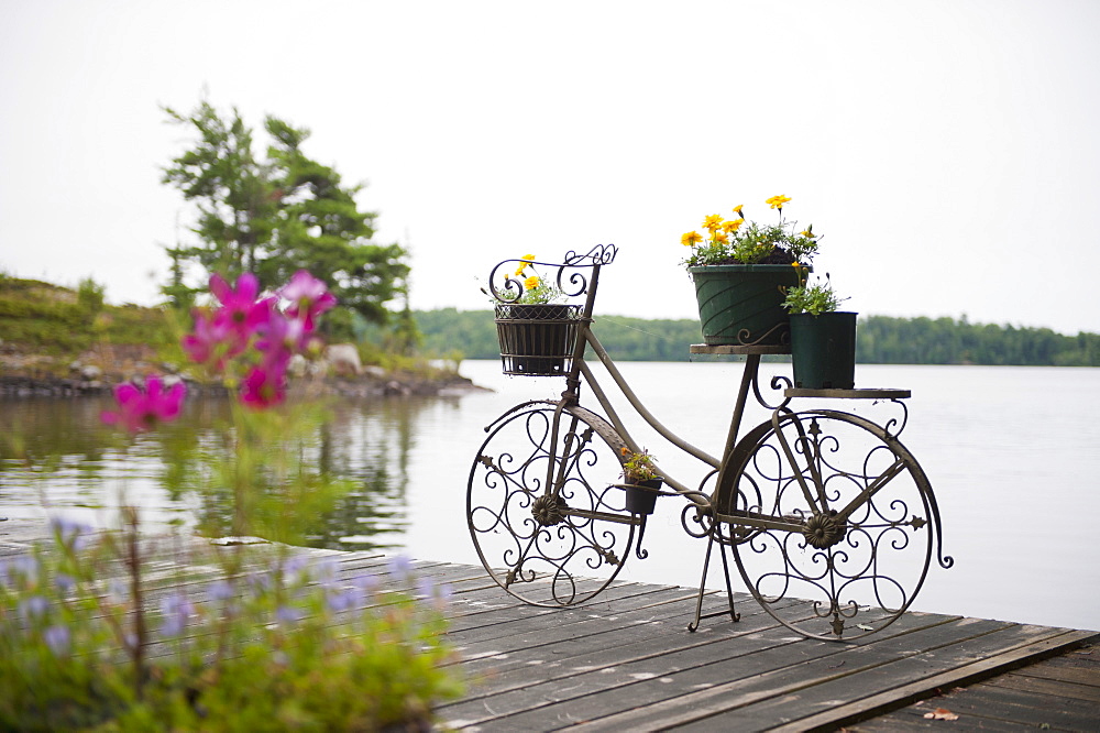 A deck on a lake with a decorative flower pot in the shape of a bicycle, kenora ontario canada