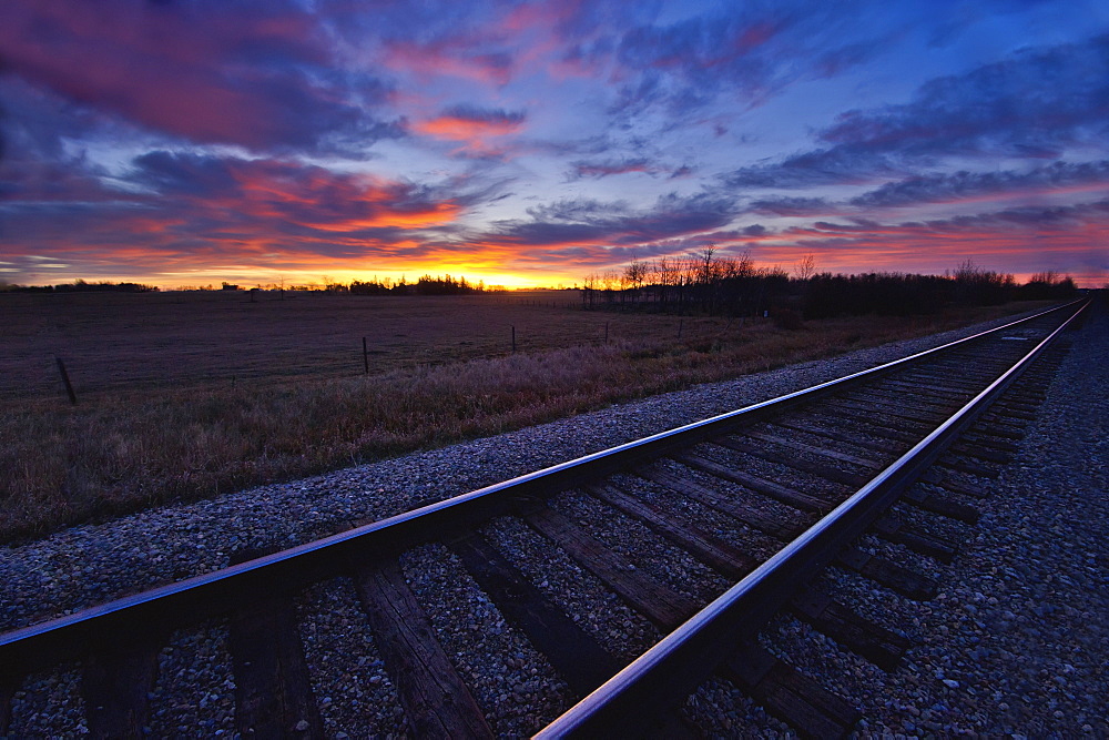 Train tracks and a dramatic colourful sky at sunset, Millet alberta canada